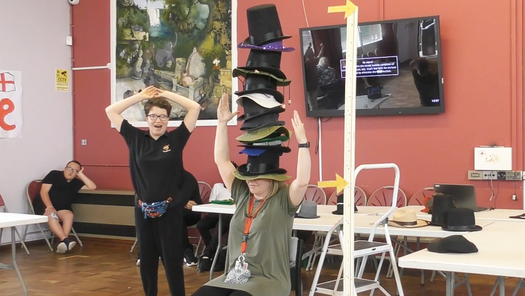 Students stack 15 hats on teacher's head to break record