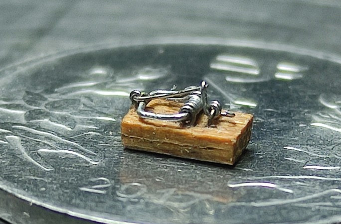 tiny mousetrap on top of coin