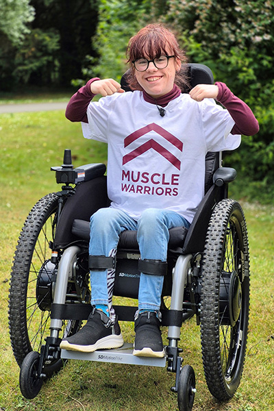 Carmela in her wheelchair flexing her arm muscles 