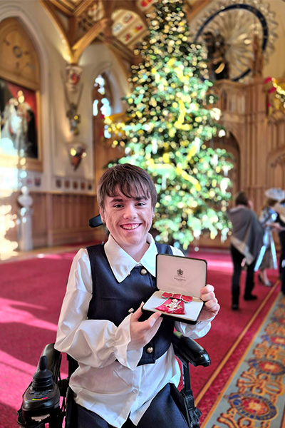 Carmela with her MBE medal in front of a Christmas tree