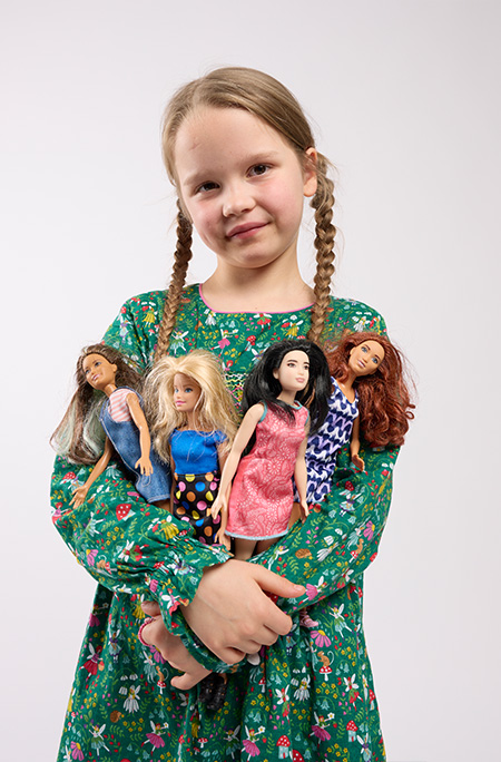 Girl holding four Barbie dolls