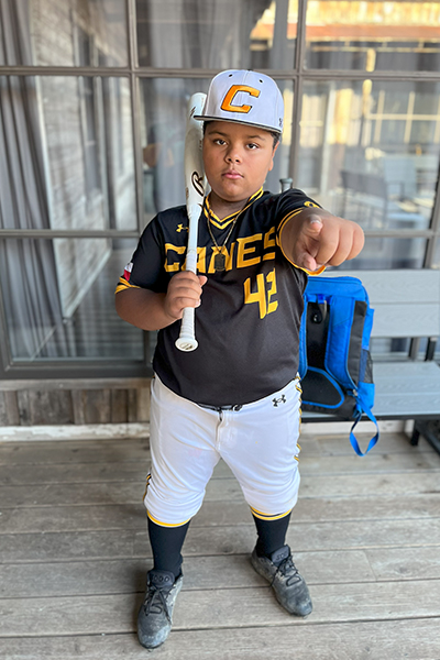 Cavanaugh Bell holding a baseball bat against his shoulder and pointing at the camera