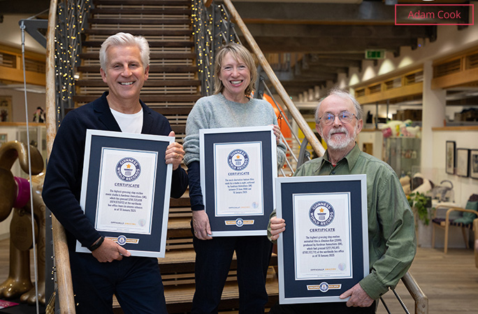 Three employees from Aardman stood on a staircase holding their GWR certificates