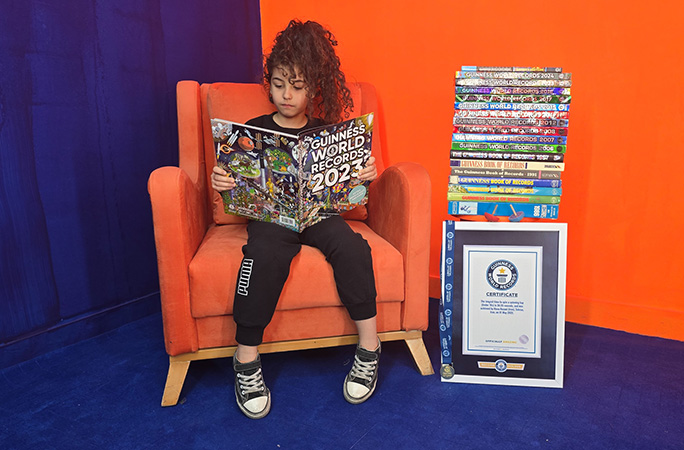 Hana sat in a chair reading a GWR book next to her certificate and a pile of GWR books