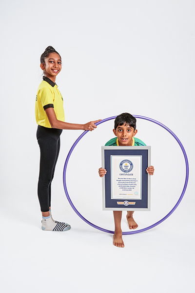 Mamathi holding a hoop and Bhairav going through it holding a GWR certificate