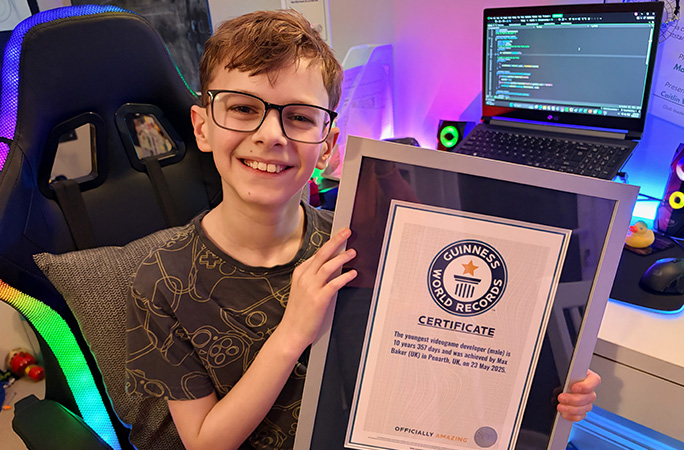 Max holding his GWR certificate sat in front of his laptop