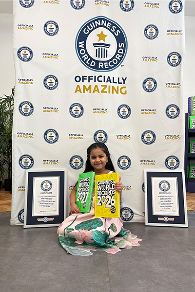 Anvi sat on the floor holding her GWR books with her certificates at either side of her