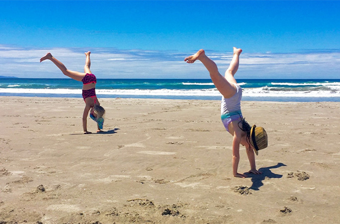 girls cartwheeling at beach