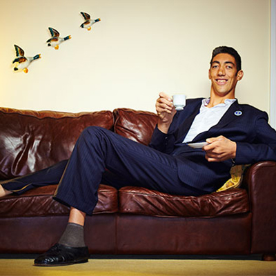 Sultan Kösen sitting on sofa holding a mug