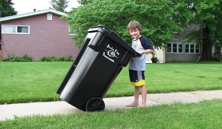 Boy carrying trash bin