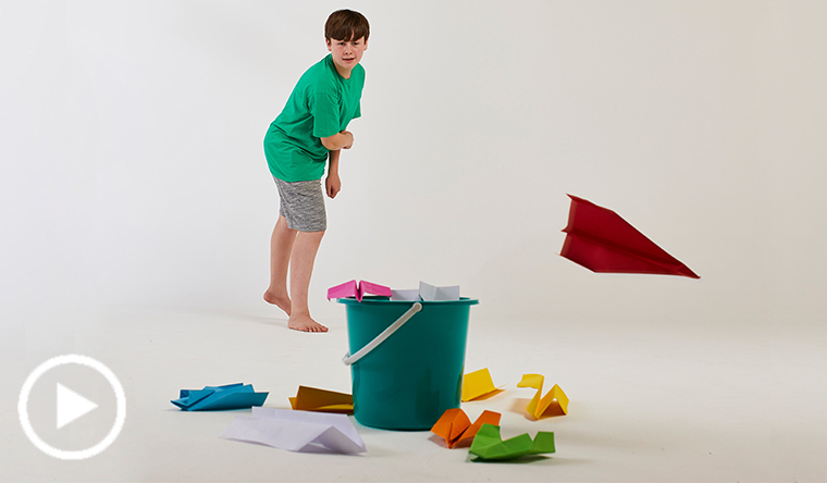 Boy throwing paper planes into bucket