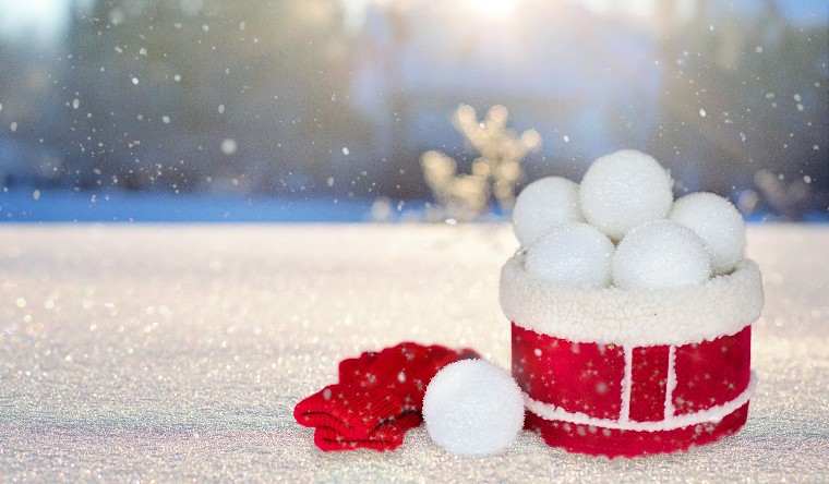 Red box containing snowballs sitting on th ground as it snows