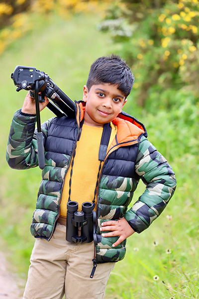 Aneeshwar carrying a camera tripod over his shoulder