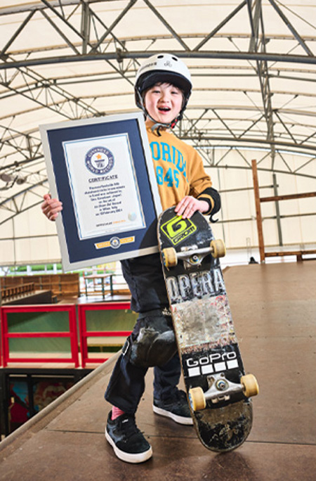 Ema posing with certificate and skateboard