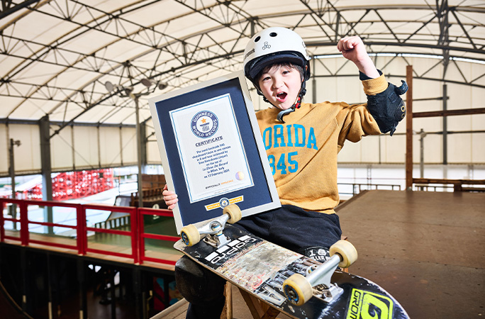 Ema posing with skateboard and certificate