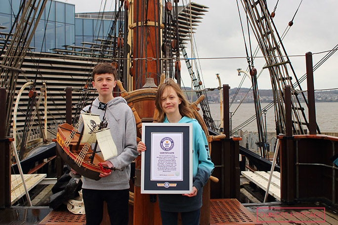 Brothers with boat and certificate