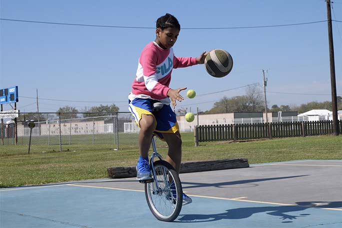 zaila playing basketball on a unicycle