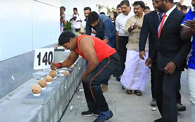 man smashing coconuts with head